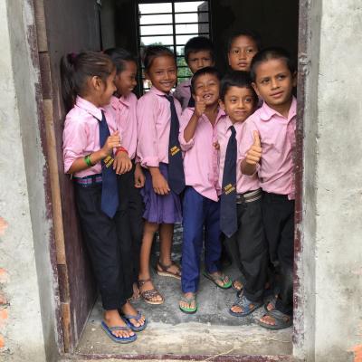 Students smile as their volunteer teacher approaches their classroom in Nepal. Students stand in the doorway of their classroom in Nepal.